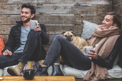 A man and a woman smiling while drinking coffee