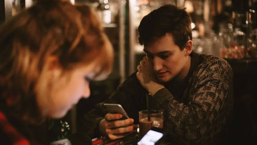 A man and woman looking at their phones