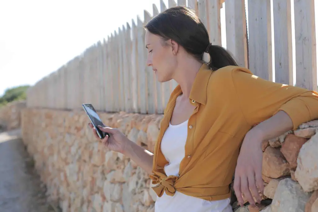 Woman looking at her phone whole leaning on a wall 