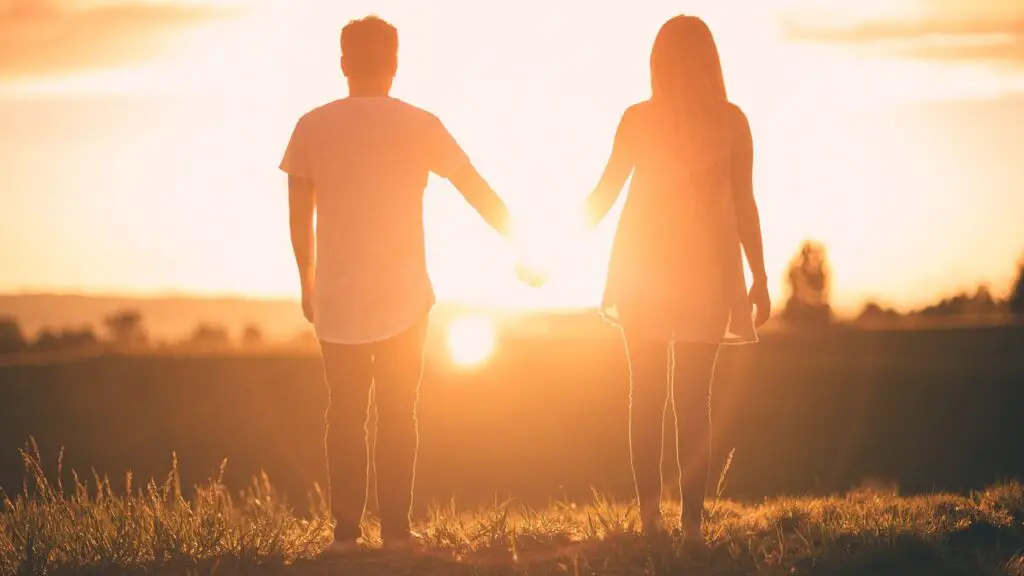 A girl and boy holding hands while watching sunset